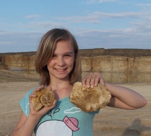Julia with two of her finds, a maclurite and  a rare Ordovician chain coral.