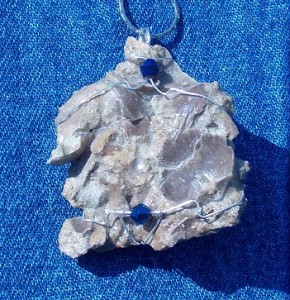 A brachiopod hash plate encased in silver with blue beads.